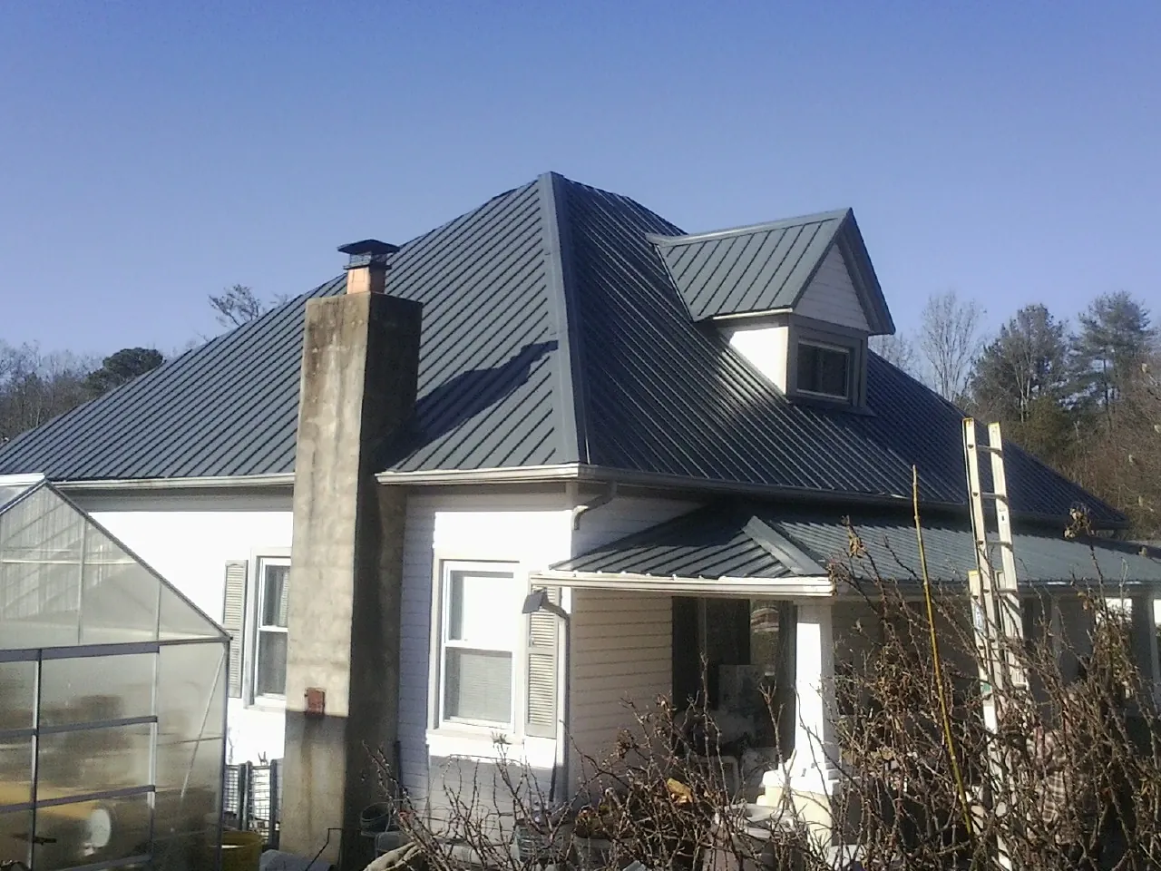 Dark blue standing seam metal roof on a white farmhouse with dormer — Slate & Tile Roof Repair by Roofing Brothers in Winlock