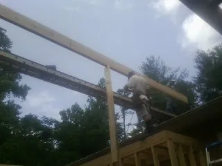 Carpenter setting a ridge beam over a new addition frame — Ice Dam Removal by Roofing Brothers in Winlock