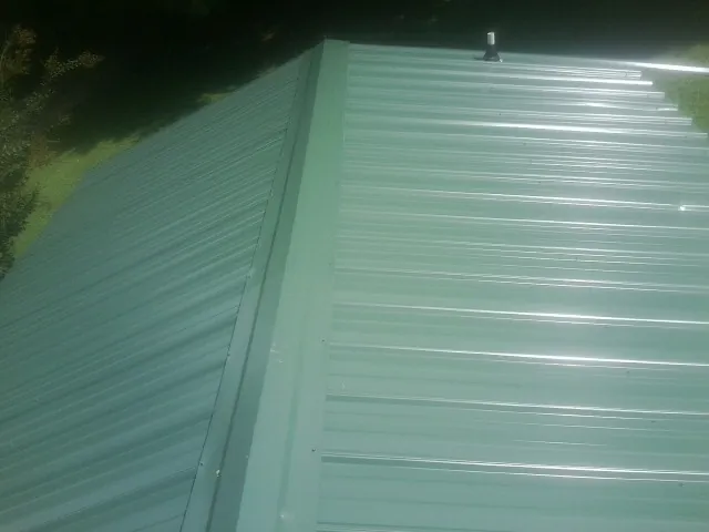New green metal panels meeting at the ridge of a roof — Flat Roof Repair work by our crew in Winlock