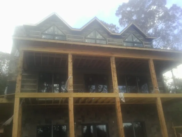 Dormers and porch framing on a large log home under construction — Roof Coating work by our crew in Winlock