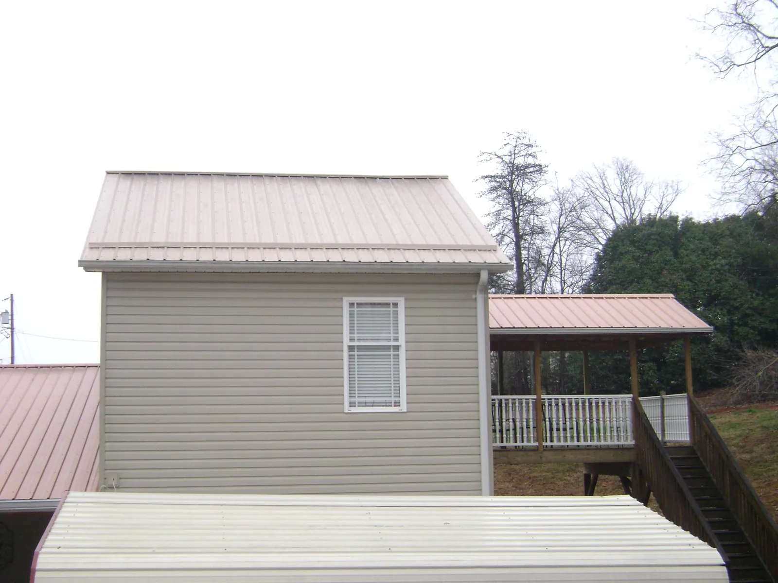 Tan metal roofs on a two story addition and attached porch, from a Roof Replacement job in Winlock