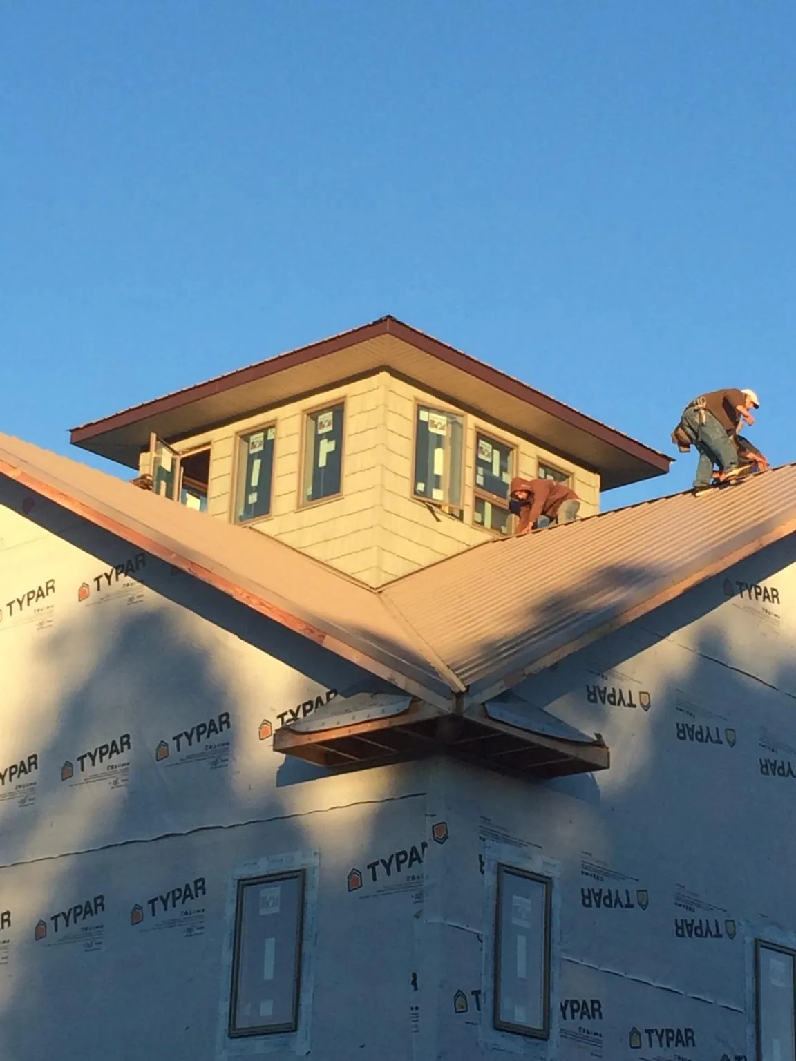 Roofers working around a rooftop cupola on a new metal roof at sunset — Roof Waterproofing in Winlock by Roofing Brothers